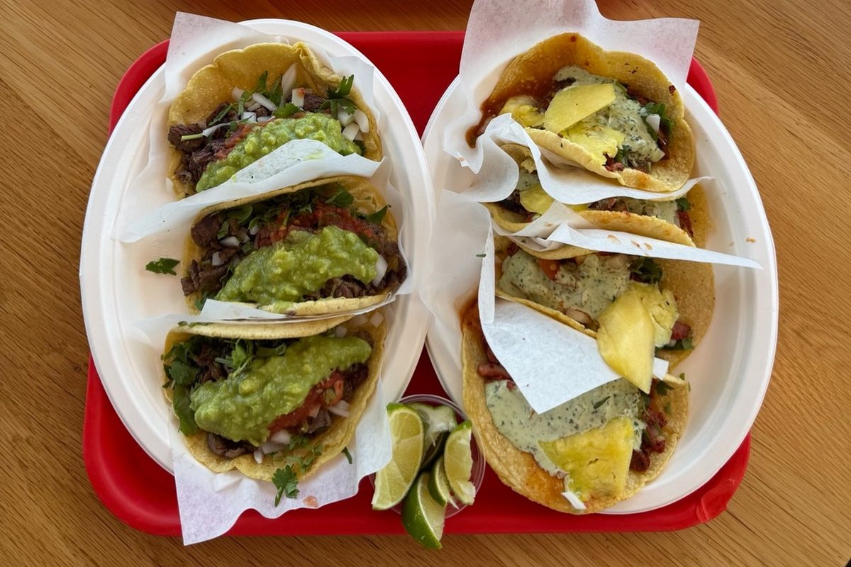 Al pastor tacos with pineapple next to carne asada tacos with guacamole on a red tray at Taco Viva in Phoenix