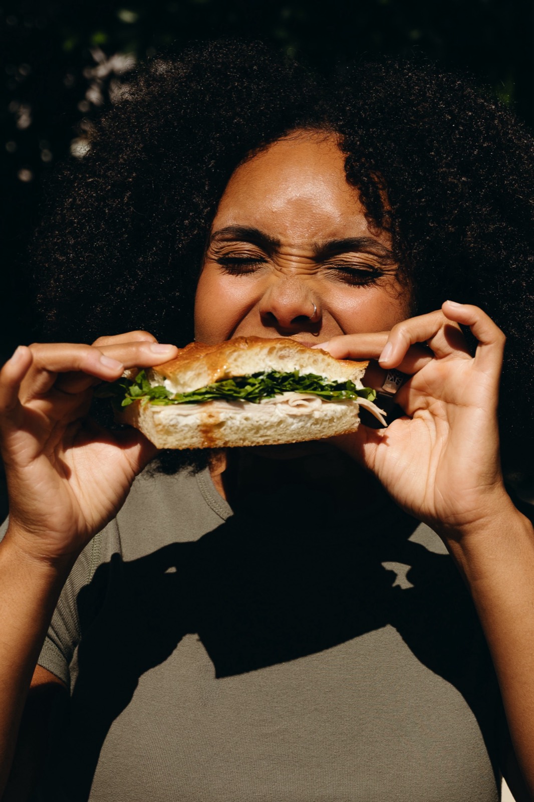 Customer biting into a Hall Pass sandwich in the sun